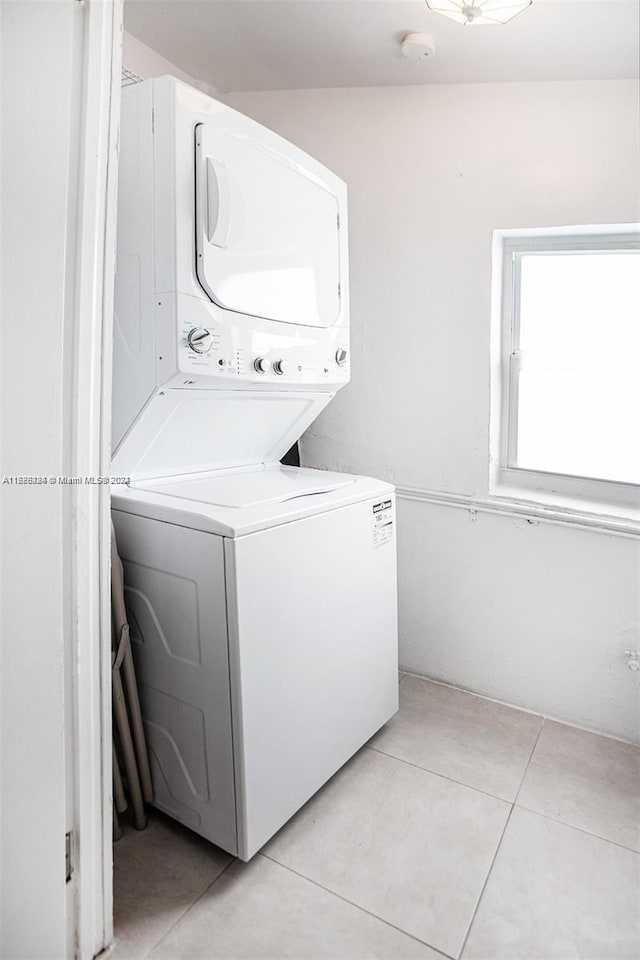 laundry room with stacked washer / dryer and light tile patterned floors