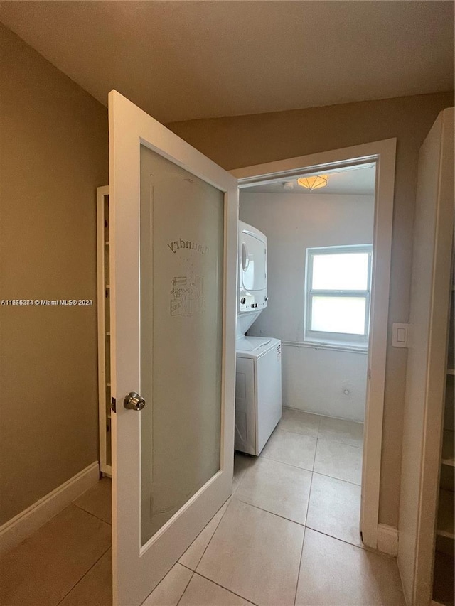 laundry room with stacked washer and clothes dryer and light tile patterned floors