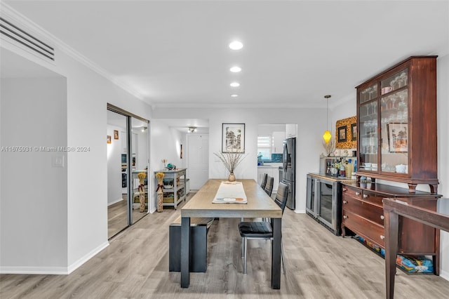 dining room with light hardwood / wood-style floors, wine cooler, and ornamental molding