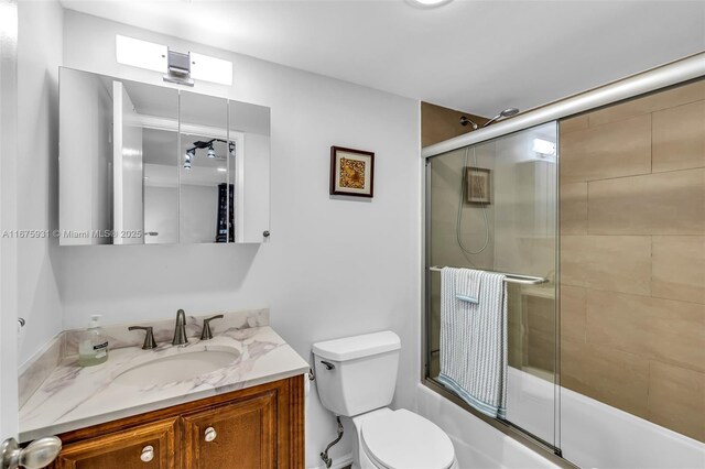 full bathroom featuring vanity, toilet, and combined bath / shower with glass door