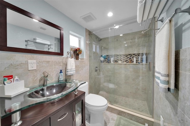 bathroom featuring toilet, tile walls, vanity, and a shower with shower door