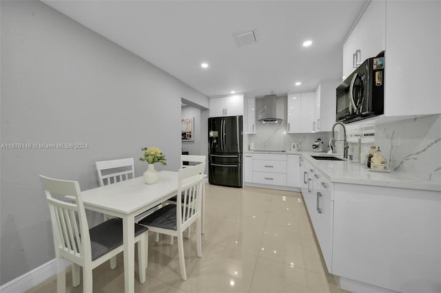 kitchen featuring white cabinets, sink, tasteful backsplash, wall chimney range hood, and refrigerator with ice dispenser