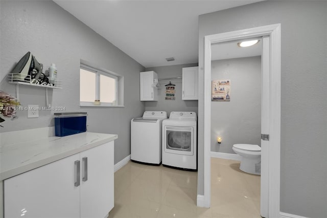 clothes washing area with washer and clothes dryer, cabinets, and light tile patterned floors