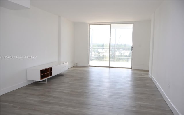 unfurnished room with floor to ceiling windows, wood finished floors, and baseboards