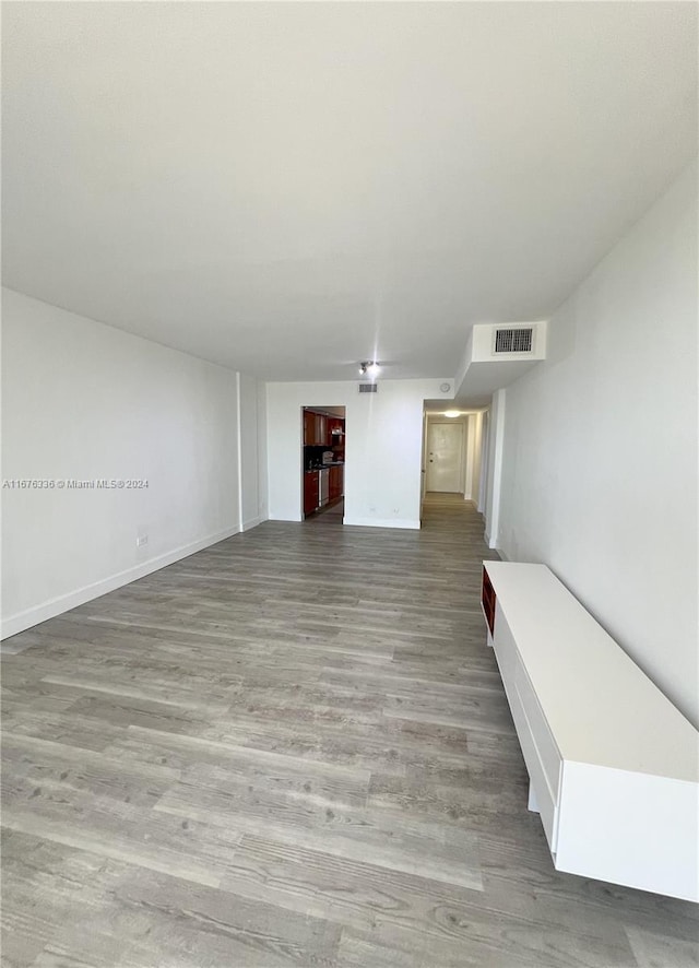 unfurnished living room with visible vents, wood finished floors, and baseboards