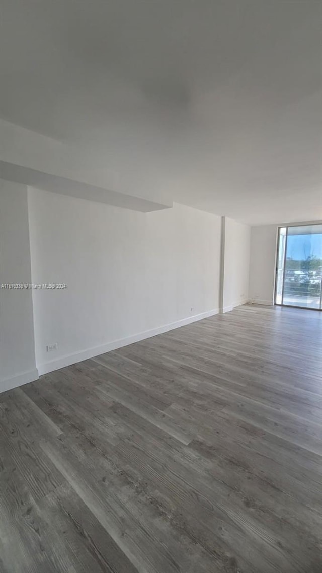 spare room with baseboards and dark wood-type flooring