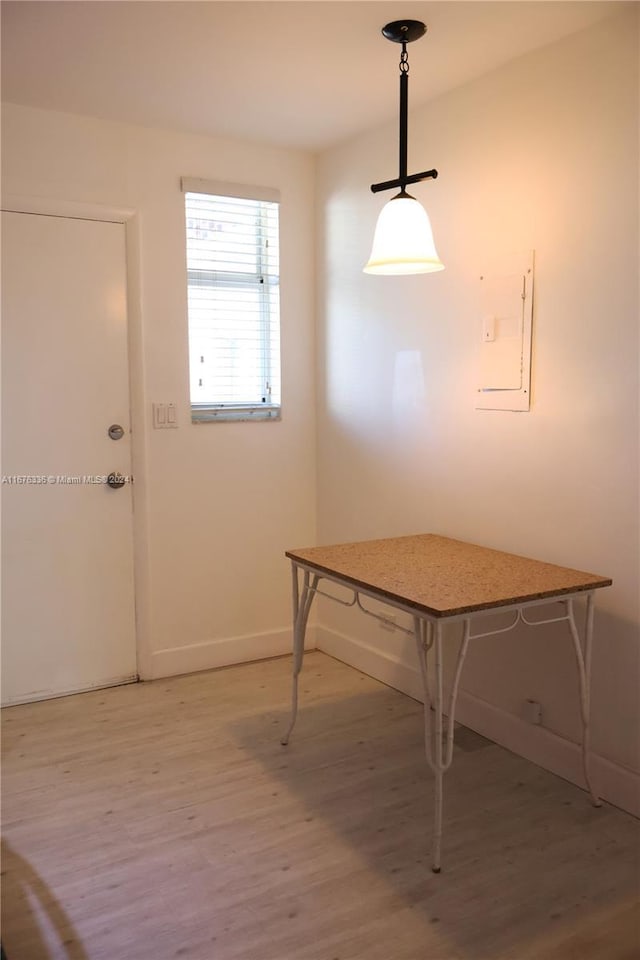 unfurnished dining area featuring baseboards and light wood finished floors