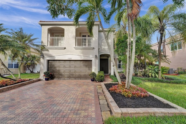 mediterranean / spanish-style home with a balcony, central AC unit, and a garage