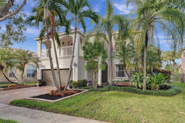 mediterranean / spanish house featuring a balcony, a front lawn, and a garage