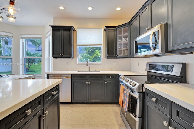 kitchen featuring appliances with stainless steel finishes, sink, backsplash, hanging light fixtures, and light tile patterned floors