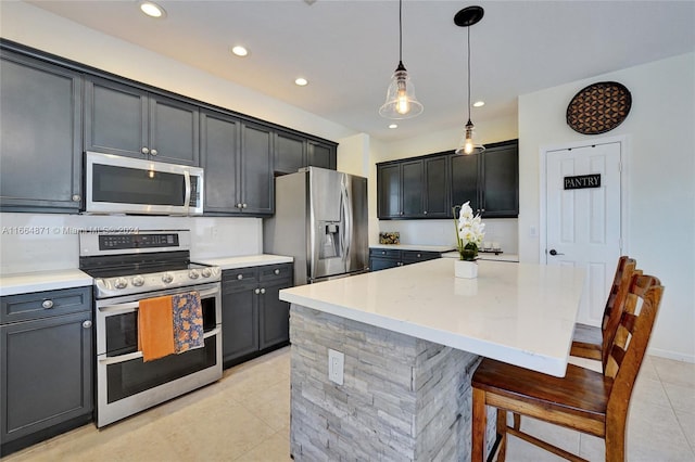 kitchen featuring a kitchen island, appliances with stainless steel finishes, a breakfast bar, light tile patterned flooring, and decorative light fixtures