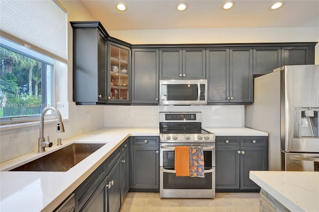 kitchen with appliances with stainless steel finishes, decorative backsplash, sink, and light stone counters