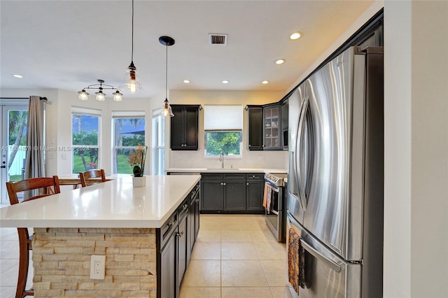 kitchen with sink, a center island, light tile patterned flooring, pendant lighting, and appliances with stainless steel finishes