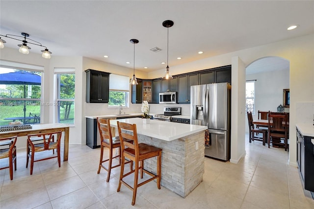 kitchen featuring sink, appliances with stainless steel finishes, a center island, and decorative light fixtures