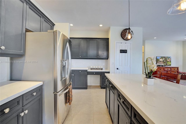 kitchen with stainless steel fridge with ice dispenser, light stone counters, light tile patterned floors, and pendant lighting