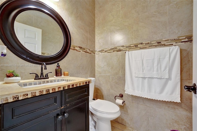 bathroom with tile walls, vanity, and toilet