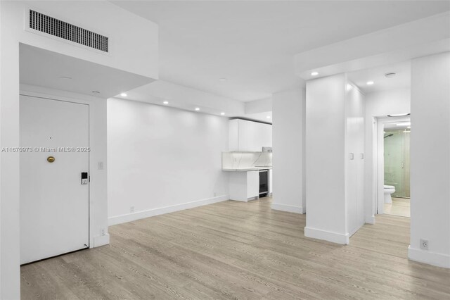 spare room featuring ceiling fan, a barn door, and light hardwood / wood-style floors