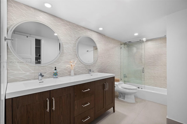 full bathroom featuring tile walls, bath / shower combo with glass door, vanity, tile patterned floors, and toilet