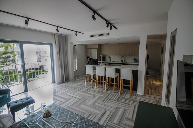 kitchen with white refrigerator with ice dispenser, sink, a kitchen bar, and rail lighting