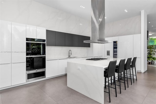 kitchen with white cabinets, sink, a spacious island, island exhaust hood, and stainless steel gas stovetop