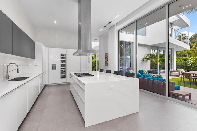 kitchen with white cabinets, a healthy amount of sunlight, sink, a center island, and stainless steel gas stovetop