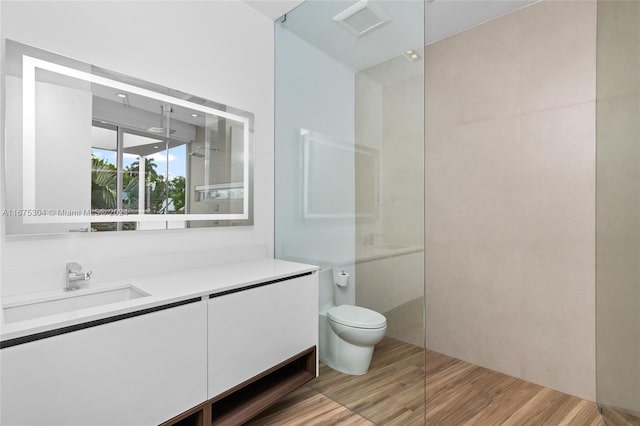 bathroom with vanity, hardwood / wood-style flooring, toilet, and walk in shower