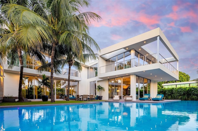 pool at dusk featuring a patio area