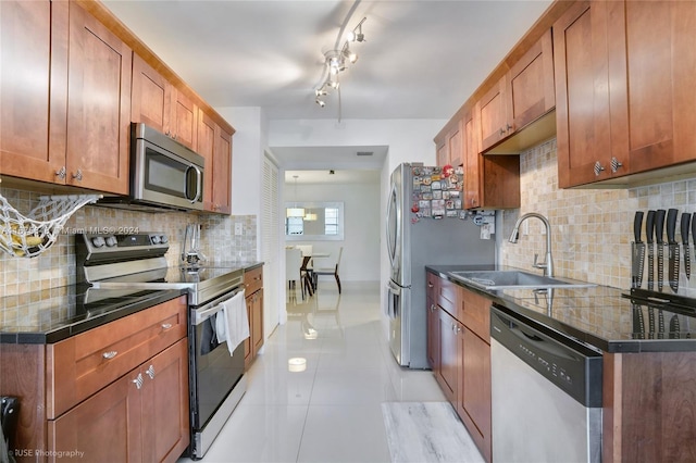 kitchen featuring light tile patterned flooring, appliances with stainless steel finishes, sink, and decorative backsplash