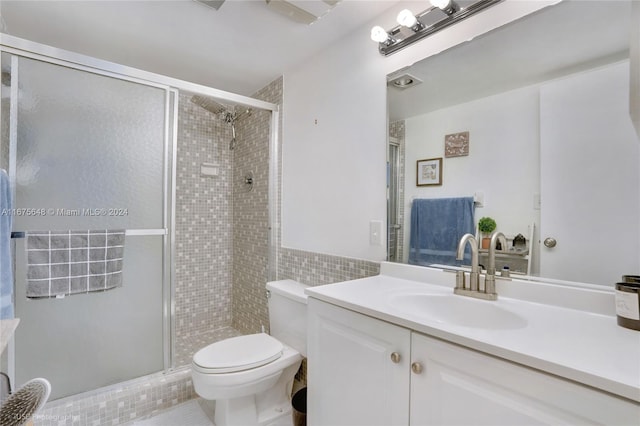 bathroom featuring vanity, a shower with door, toilet, and tile walls