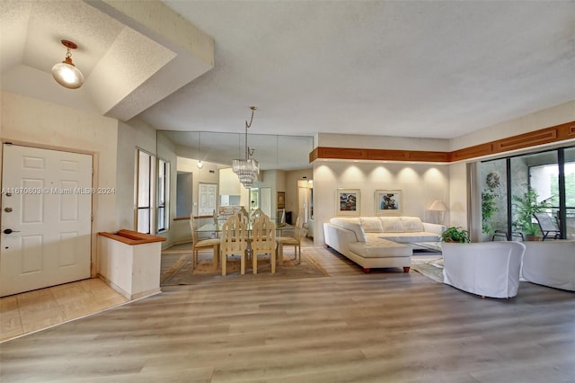 living room with a textured ceiling, light hardwood / wood-style flooring, and lofted ceiling