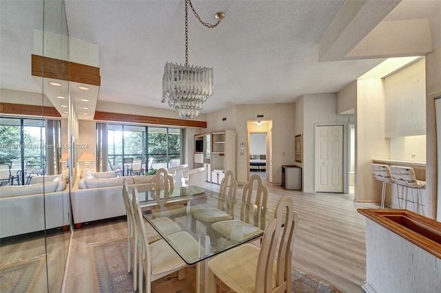 dining area featuring a textured ceiling, an inviting chandelier, light hardwood / wood-style flooring, and plenty of natural light