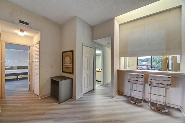 hallway featuring a textured ceiling and light hardwood / wood-style flooring