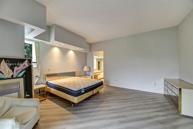 bedroom featuring ensuite bathroom, hardwood / wood-style floors, and a textured ceiling