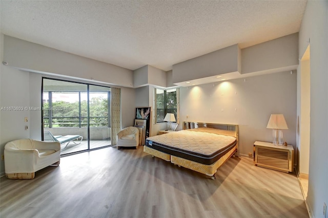 bedroom with a textured ceiling, access to outside, and light hardwood / wood-style floors