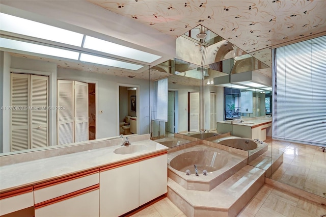 bathroom featuring tile patterned flooring, vanity, a tub to relax in, and a skylight