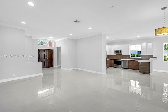 kitchen with appliances with stainless steel finishes, sink, white cabinets, ornamental molding, and dark brown cabinetry