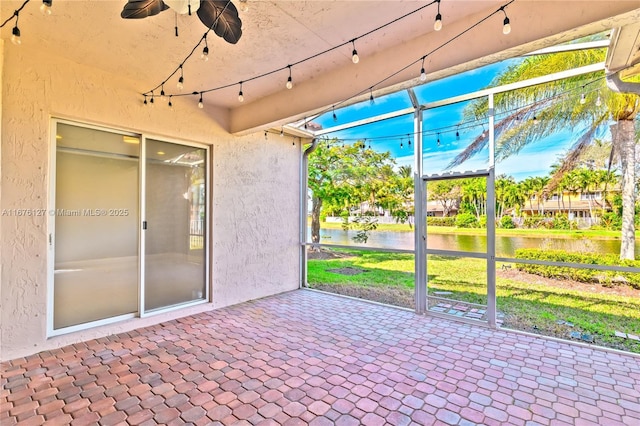 unfurnished sunroom featuring ceiling fan and a water view