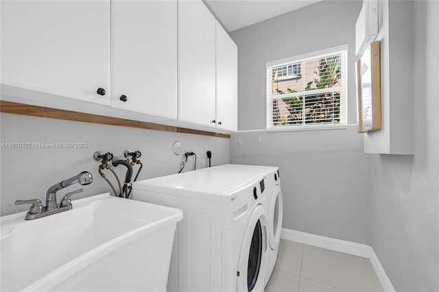 clothes washing area with sink, cabinets, washing machine and clothes dryer, and light tile patterned flooring