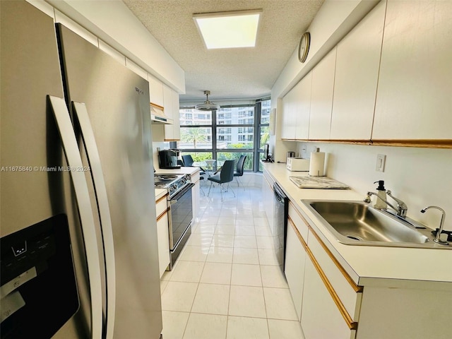 kitchen with white cabinets, sink, a textured ceiling, black appliances, and a wall of windows