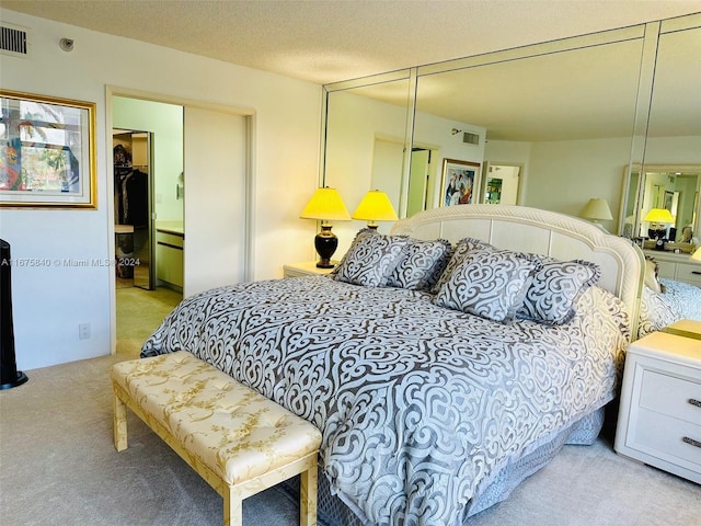 bedroom with a textured ceiling, a closet, and light colored carpet