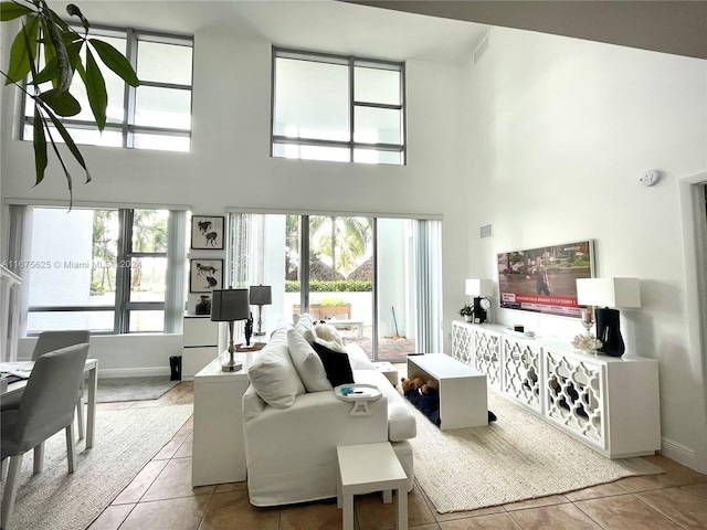 living room with a towering ceiling and light tile patterned floors