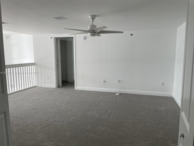 spare room featuring dark colored carpet and ceiling fan