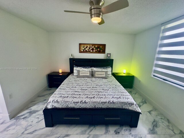 bedroom with ceiling fan and a textured ceiling