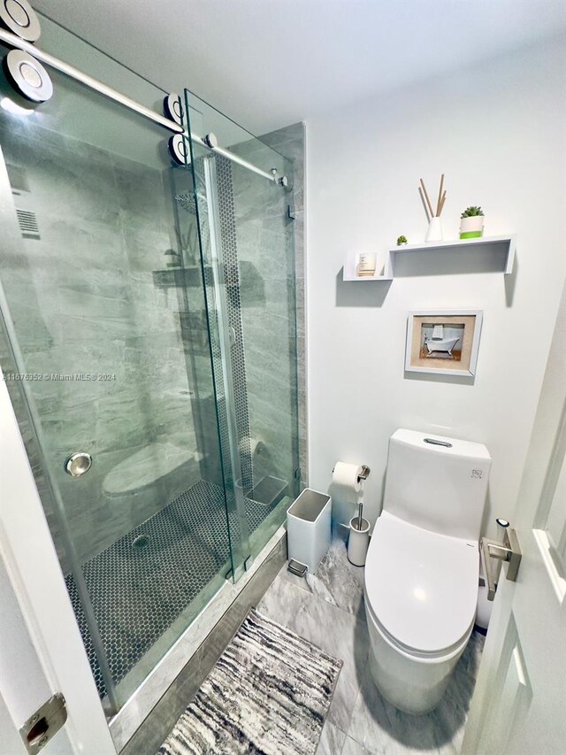 bathroom with toilet and a shower with door