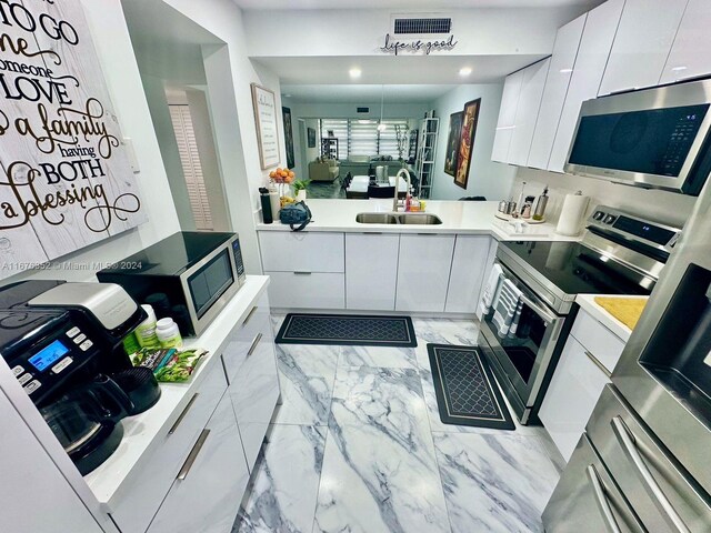 kitchen with white cabinets, stainless steel appliances, sink, and kitchen peninsula