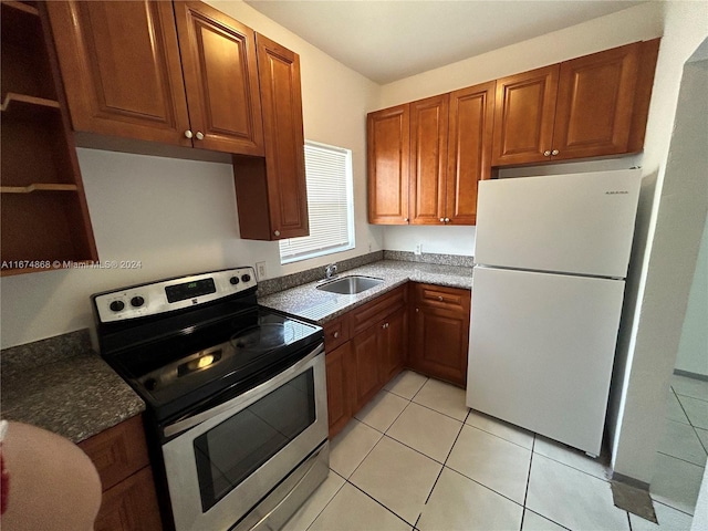 kitchen with light tile patterned floors, stainless steel electric stove, sink, and white fridge