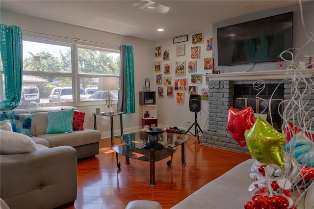 living room with a brick fireplace and hardwood / wood-style floors