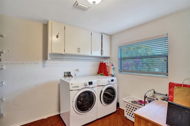 clothes washing area featuring dark wood-type flooring, washing machine and clothes dryer, cabinets, and a textured ceiling