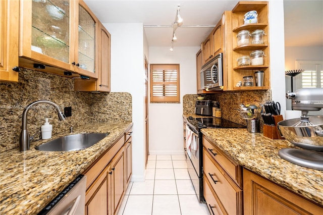 kitchen featuring decorative backsplash, sink, light stone countertops, appliances with stainless steel finishes, and rail lighting