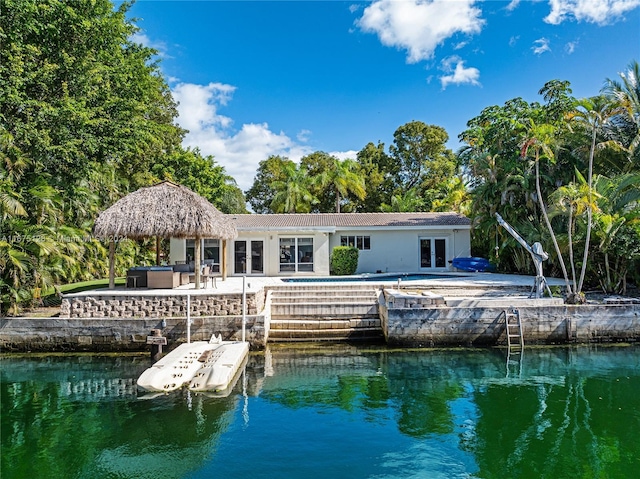 back of property featuring an outdoor pool, a gazebo, stucco siding, a patio, and a water view